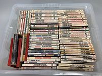 Overhead shot showing a large bin filled with multiple stacks of vintage paperback books, mostly Edgar Rice Burroughs titles and others. Books are arranged horizontally and vertically within a plastic bin.