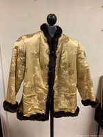 Front view of a gold Chinese silk jacket with floral jacquard pattern and dark brown rabbit fur trim along the collar, front opening, cuffs, and hem.