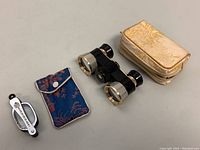 Overview photo of all items showing compact reading glasses with blue fabric case and vintage Elite opera glasses with cream fabric case.