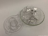 Assorted small glassware items including creamer, sugar bowl, salt and pepper shakers, and dessert bowls shown in a shallow serving dish.