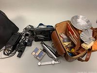 Lot contents with Sony CCD-TR23 video recorder, power adapter, leather camera case, silver reflector and other photography accessories visible