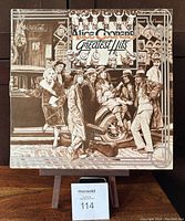 Front cover of Alice Cooper Greatest Hits 1974 vinyl LP showing illustrated vintage street scene with people and car.
