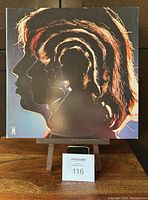 Front cover of Rolling Stones Hot Rocks 1964-1971 double LP showing stylized nested profiles of the band members with fiery hair details on black background.
