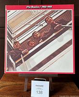 Front cover of The Beatles 1962-1966 double vinyl LP showing band members looking down a stairwell, red border and white text.