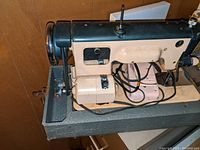 Side view of vintage sewing machine showcasing metal components, cords and foot pedal.