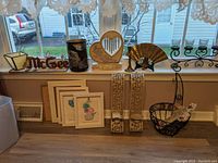 Wide shot showing multiple decorative items along window ledge and floor including frames, candle holders, memorial decor and fruit basket.