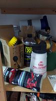 Overview photo showing various car cleaning supplies including yellow brushes, spray bottles, and a metal funnel on shelf
