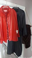 Red Remy leather jacket, black TiRaGE by Couger leather coat, and dark brown mink fur stole hanging on hangers.