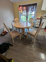 Full view of round pedestal table with four matching chairs around it