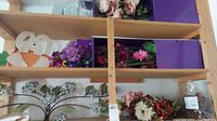 Shelves with purple dried flower bouquets, metal floral wall art, and other floral decor items