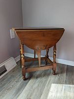 Side view of gateleg side table with leaf down, showing turned legs and base