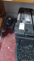 Photo of large black Black and Decker toolbox closed with some tools and cases leaning next to it.