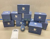 Photo showing 10 Wedgwood blue boxes with one bottle vase out in front