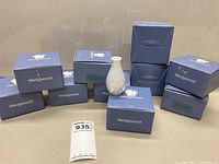 Photo of 10 Wedgwood blue boxes arranged with one boxed vase and one vase displayed outside the boxes