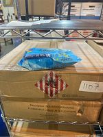 Pack of blue antibacterial hand wipes resting on a cardboard box on a metal shelf.