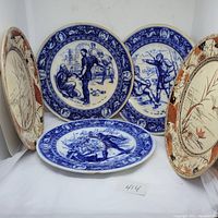 Five antique plates arranged with three Ivanhoe blue and white plates in the center and two Doulton Kudos plates flanking them, showing detailed scenes and floral patterns.