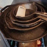 Stack of six cast iron frying pans from top view showing sizes and internal surfaces.