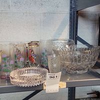 Wide angle photo showing entire grouping of vintage glassware on shelf including decorated glasses, cut glass bowls and small dish/ashtray
