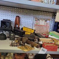 Overview of various miniature collectible items on a pegboard shelf including a Lionel Scout train car, small metal stoves, yellow train boxcar and wooden-handled tool.