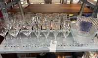 Photo of 12 wine glasses, 6 champagne flutes, and heavy textured glass ice bucket with plunger on a shelf