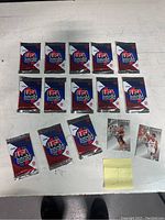 Wide shot showing 13 sealed USA Basketball card packs and 3 loose basketball player cards on white surface.