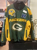 Full front view of the Green Bay Packers NFL jacket showing large team logos on chest and sleeve text.