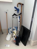 Photo of four grabbers, two canes, and various daily living aids including a sock aid, heating pad, and life planner in a corner