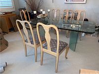 Full view of six wooden dining chairs around a glass dining table showing overall design and condition.