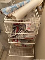 Full view of white Elfa four drawer wire storage cart filled with rolls of wrapping paper on top drawer and greeting cards in lower drawers