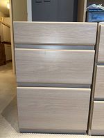 Front view of three drawer filing cabinet showing smooth drawer fronts, bottom drawer deeper for files.