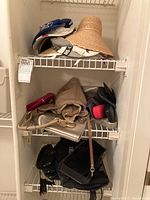 Photo of shelves displaying assorted hats including a blue Bermuda baseball cap, light gray visor, natural woven wide brim sun hat, and decorative visor hat along with various pocketbooks and eyeglass cases in different colors and sizes.