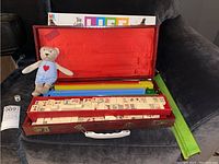 Mahjong set open displaying tiles in case, extra tile trays, Game of Life box and stuffed bear in front