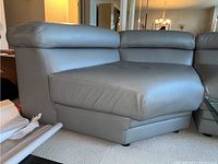 Side left view of gray leather sectional sofa corner piece showing leather texture and cushioning details