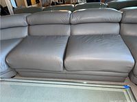 Gray two-seat modular sectional sofa section with cushioned seat and backrest cushions placed on light carpet.