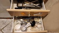 Overhead view of open drawer filled with flatware tray and loose utensils
