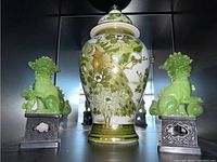 Front view of the ceramic ginger jar flanked by the green lucite Foo Dog figurines on black bases