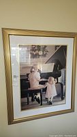 Framed signed print showing two girls playing piano, front view