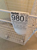 Close-up photo of the white wire storage bin showing MaxSold lot tag with lot number 980G attached to the wire frame.