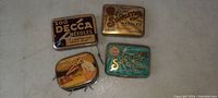 Top view showing all 4 tins with colorful logos and branding including Decca, Songster, and Victor.