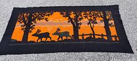 Full view of rectangular cloth rug/runner showing running elk design against orange background with black border.