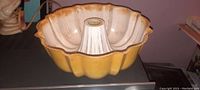Yellow antique aluminum cake mold with visible wear and used interior, showing fluted design and central tube