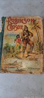 Full front cover of the Robinson Crusoe book showing the worn, illustrated cover and title.
