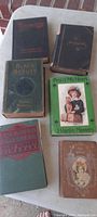 Photo showing six vintage books arranged on a table, titles visible include Black Beauty, Peg o' My Heart, The Amazing Interlude, and others.