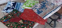 Overview of five folded pieces of vintage heavy fabric with distinct patterns and colors laid out on a surface.
