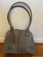 Full front view of gray handbag showing double straps and stitching detail.