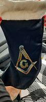 Full view of the black holiday stocking with white cuff and Masonic emblem in the center.