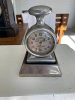Front view of antique Eclipse time stamp clock showing clock face and handle.