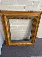 Full view of antique picture frame showing its rectangular shape, wood texture, and decorative borders.