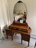 Front view of full vanity showing mirror, three-drawer riser top, lower cabinets and legs