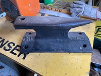 Side view of the cast iron shoe repair tie anvil showing the horn and flat base with mounting holes.